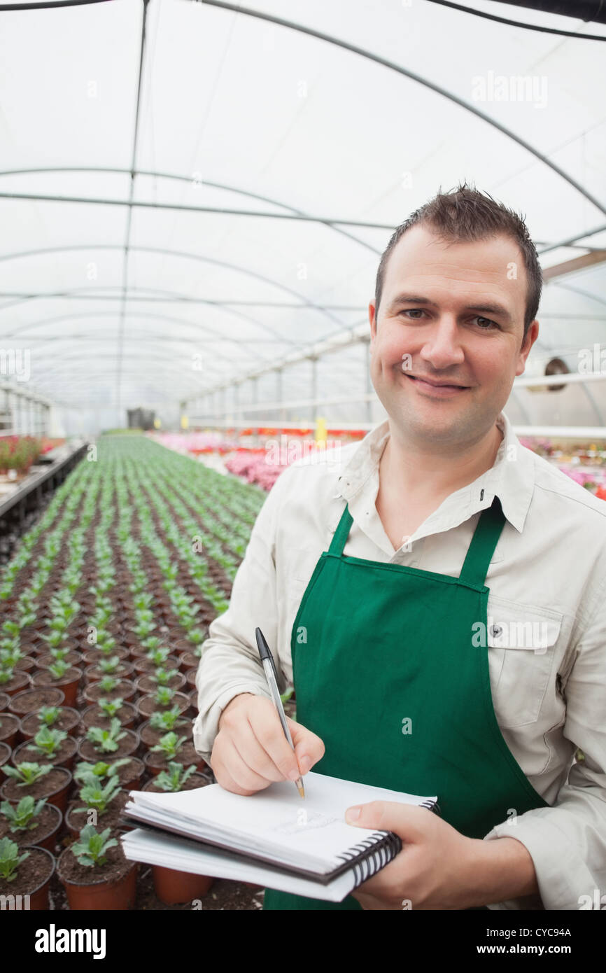 Smiling man taking notes in greenhouse Stock Photo