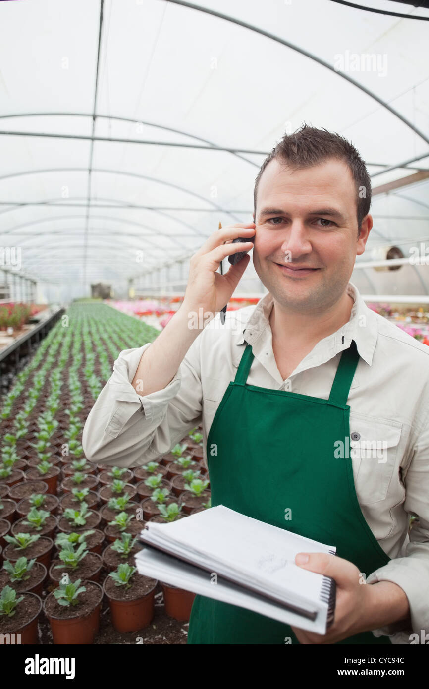Worker taking notes and calling in greenhouse Stock Photo