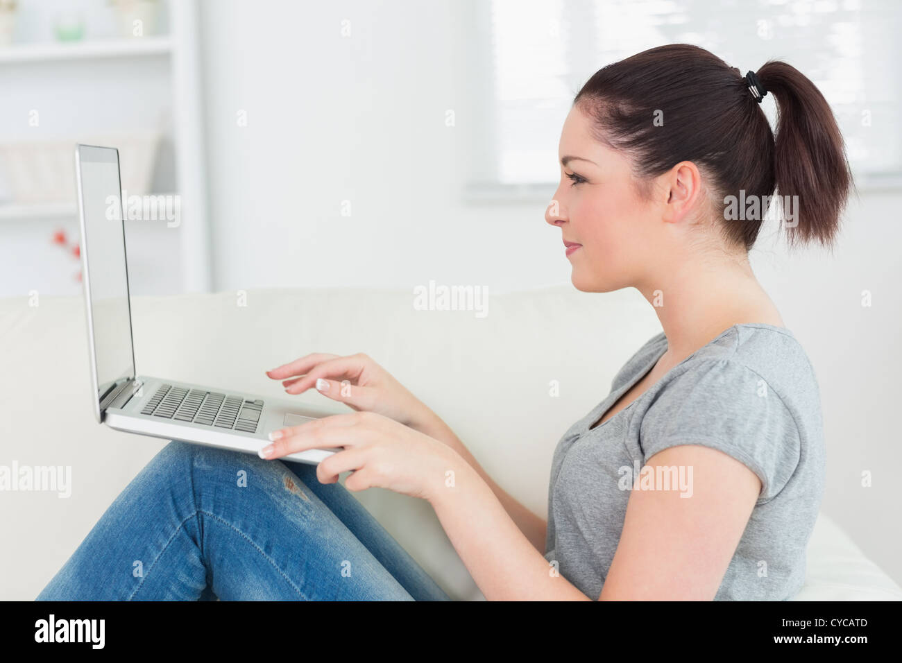 Smiling woman on the couch using a laptop Stock Photo - Alamy