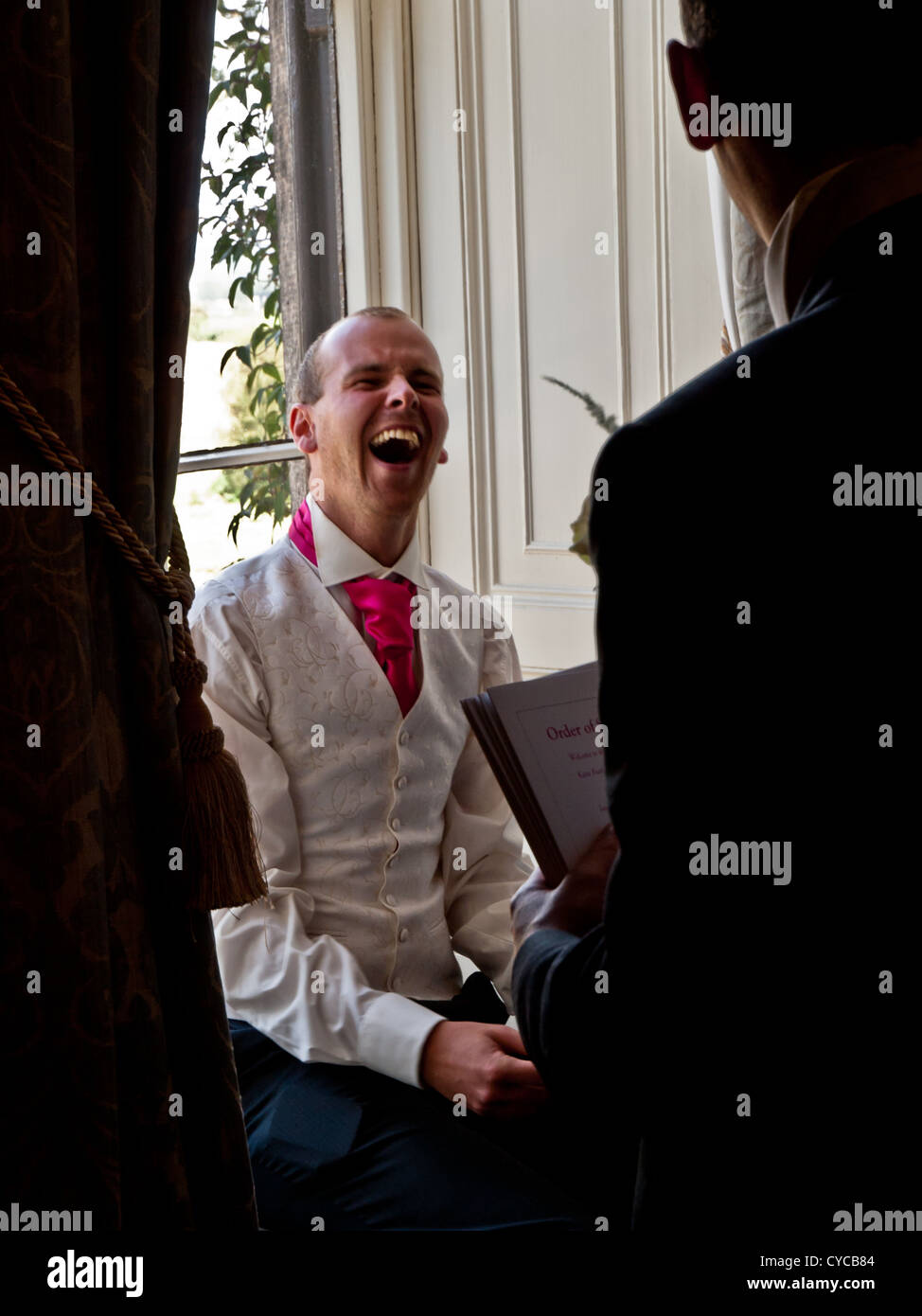 The groom laughs out loud during a light-hearted moment on his wedding day Stock Photo