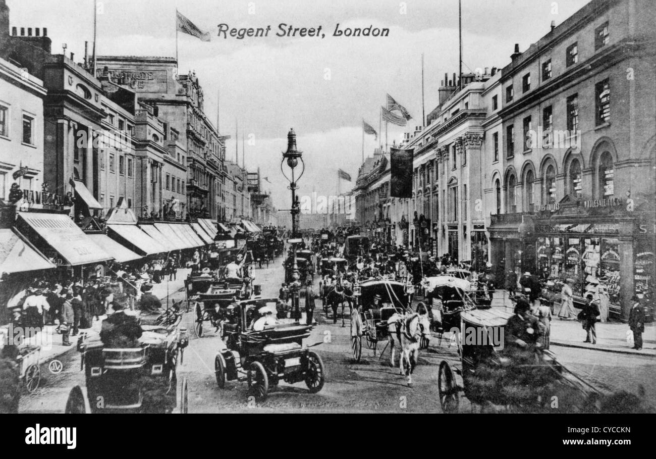 Regent Street Victorian London UK 1880s 1890s  (Centre) The motorcar or horseless carriage with woman passenger in her large fashionable hat. The car is probably a Daimler, but one of the German built Canstatt Daimlers, not a product of the Coventry based British company. It is being driven by the top hated gent sitting high over the front wheels. Traffic, hansom cabs horse drawn carriages and  crowds of people going shopping. Traffic congestion rush hour central London 1890s. On the right the women are outside 'F.S.Goss The Pharmacy Stores'  Circa 1895 Stock Photo