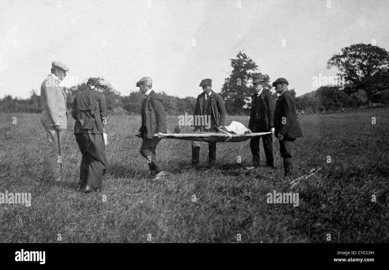 Death by misadventure 1900s UK. A group of men carry away a dead person on a stretcher probably a farm worker. Stock Photo
