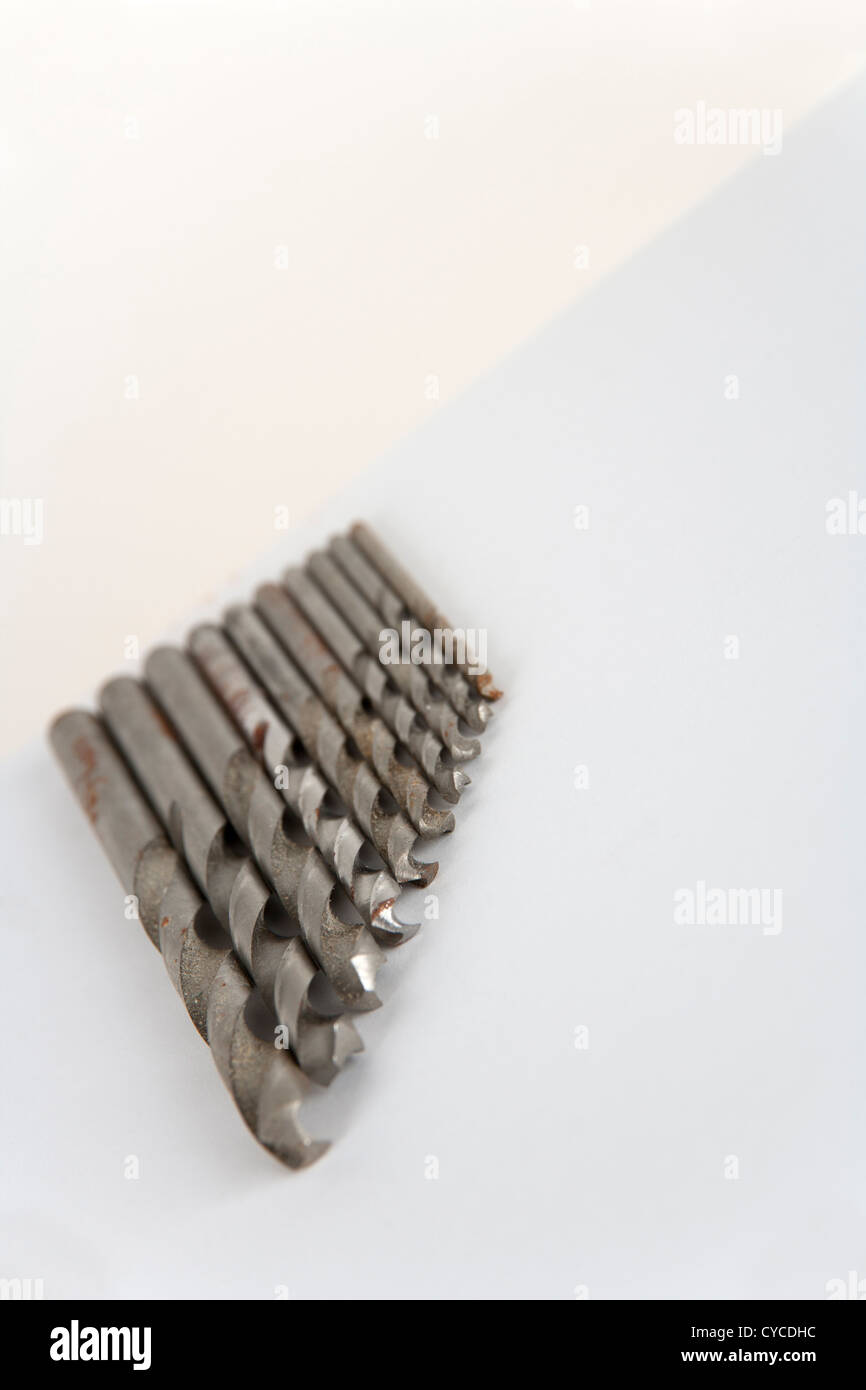 Well used and rust specked twist drill bits on white paper with copy space. Shallow depth of field. Stock Photo