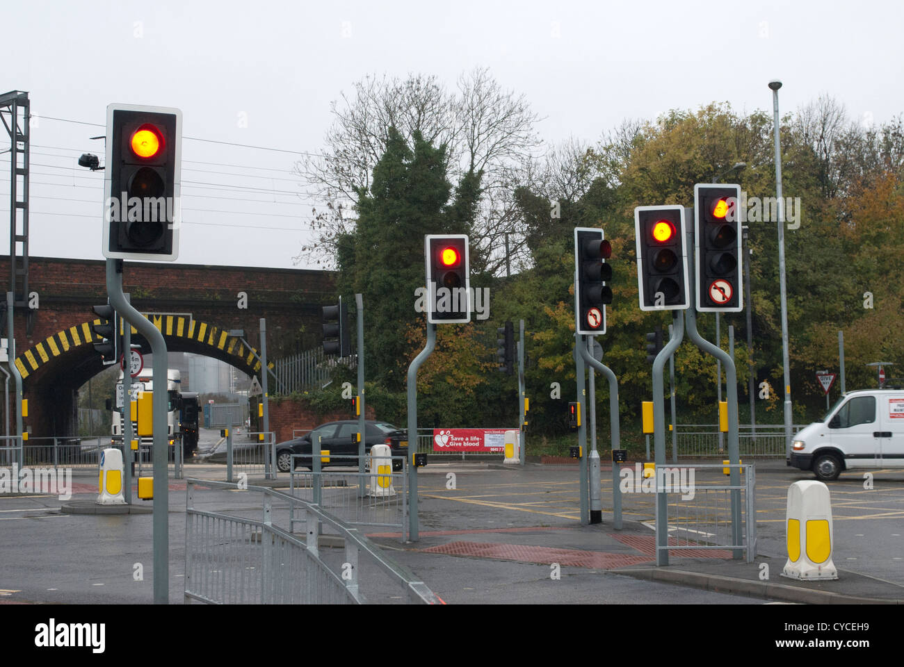 Complex set of traffic lights and pedestrian crossing lights with rail bridge in background with lights on red Stock Photo