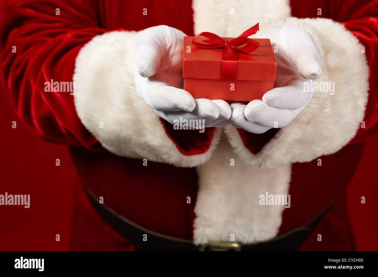 Photo of Santa Claus gloved hands holding red giftbox Stock Photo - Alamy
