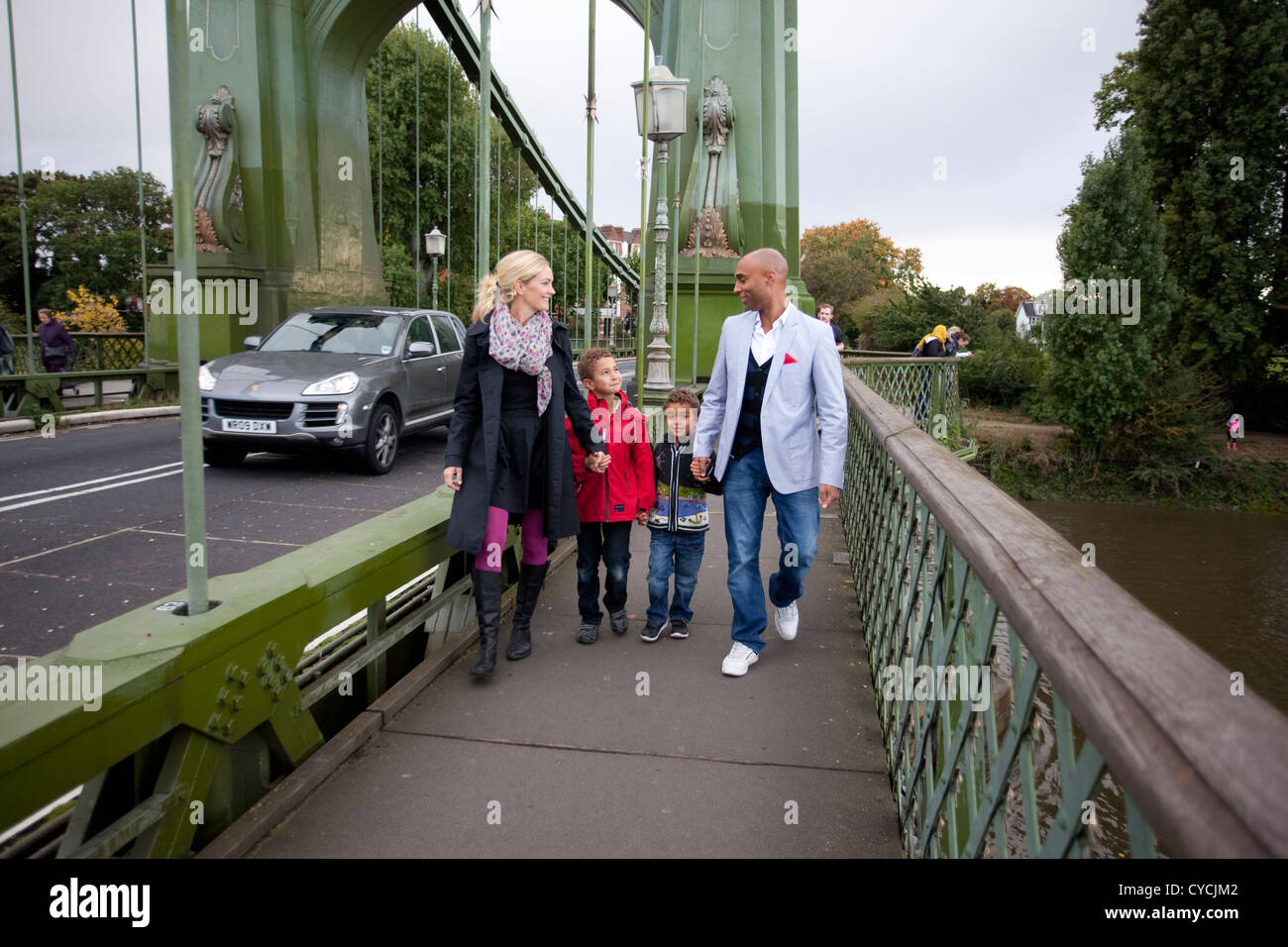 Young professional family walking across Hammersmith Bridge in West London, England, UK Stock Photo