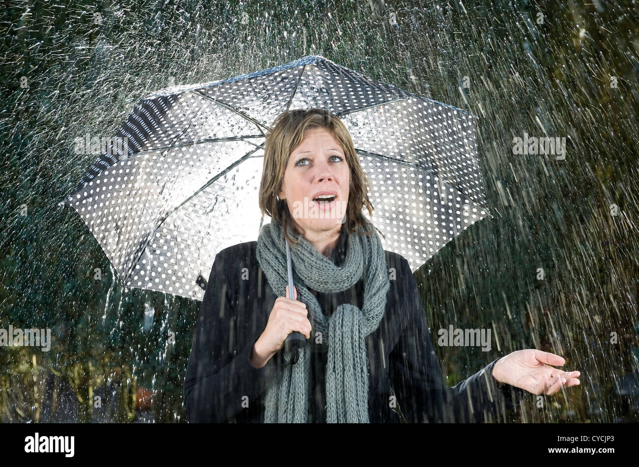 A woman under an umbrella during heavy rainfall Stock Photo