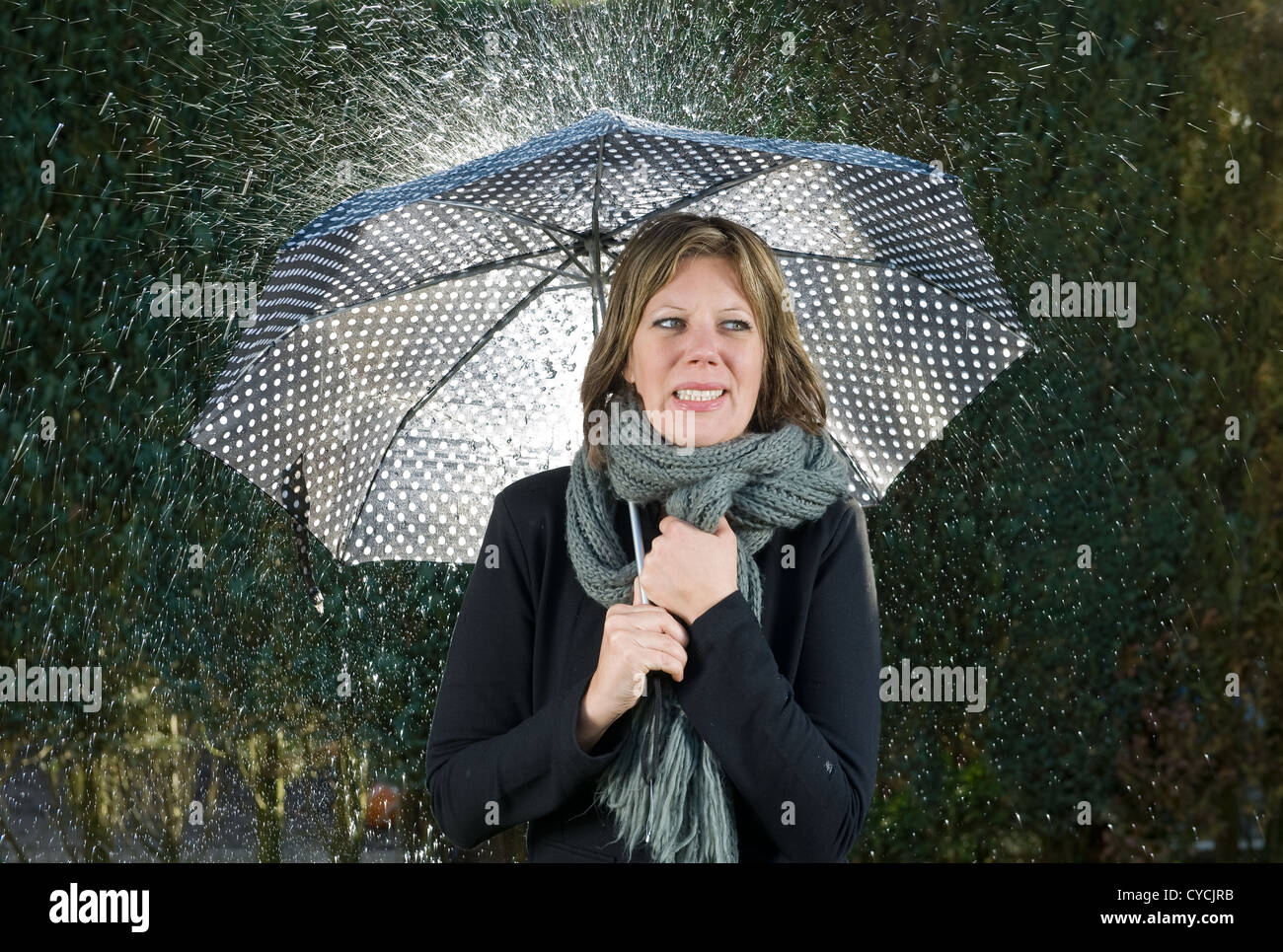 A woman under an umbrella during heavy rainfall Stock Photo