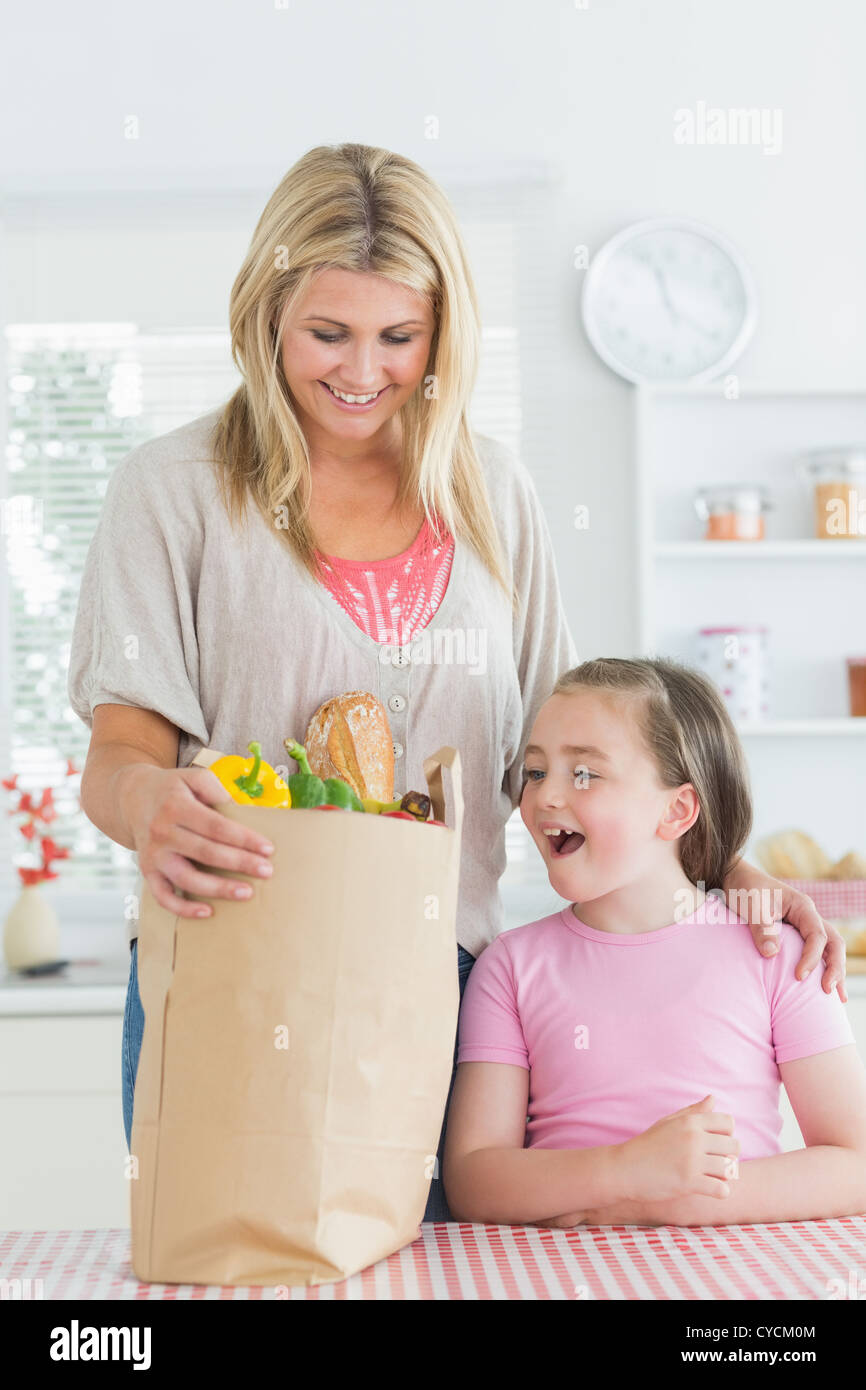 Woman looking into grocery bag beside smiling daughter Stock Photo Alamy