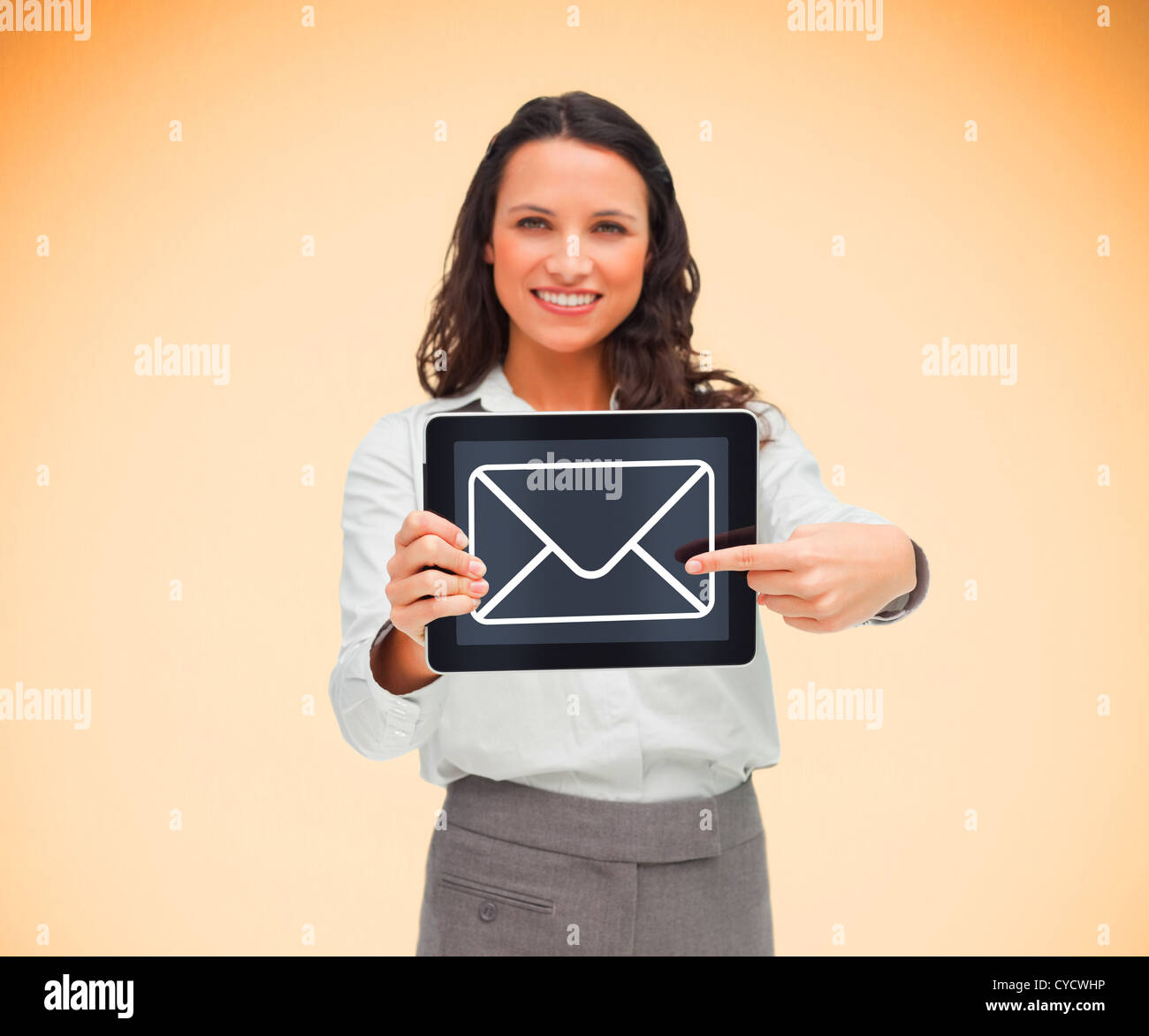 Businesswoman holding a tablet pc smiling and pointing at mail symbol Stock Photo