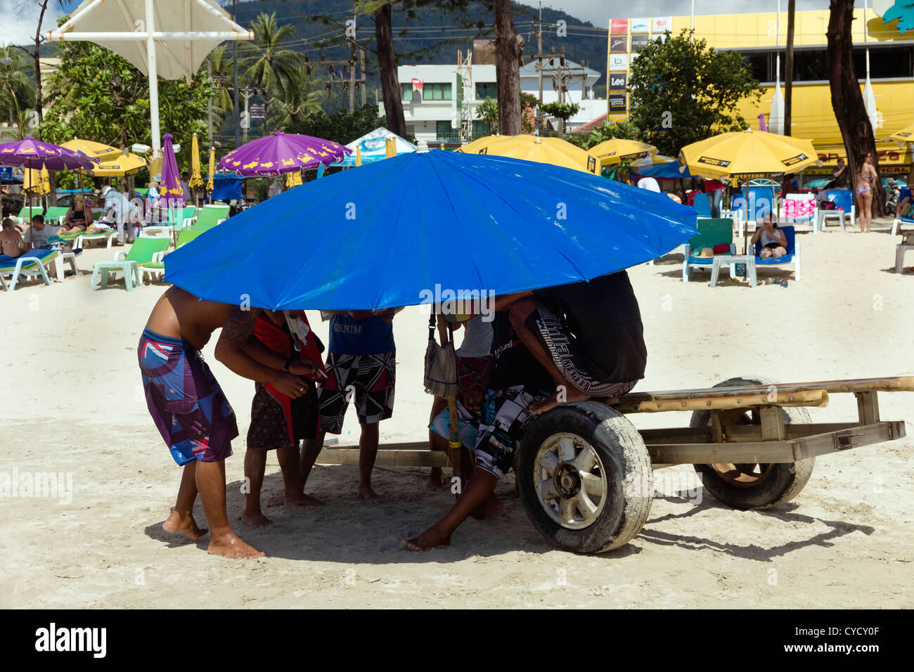Jet Ski Vendors Hide from the Sun Under a Beach Umbrella Stock Photo