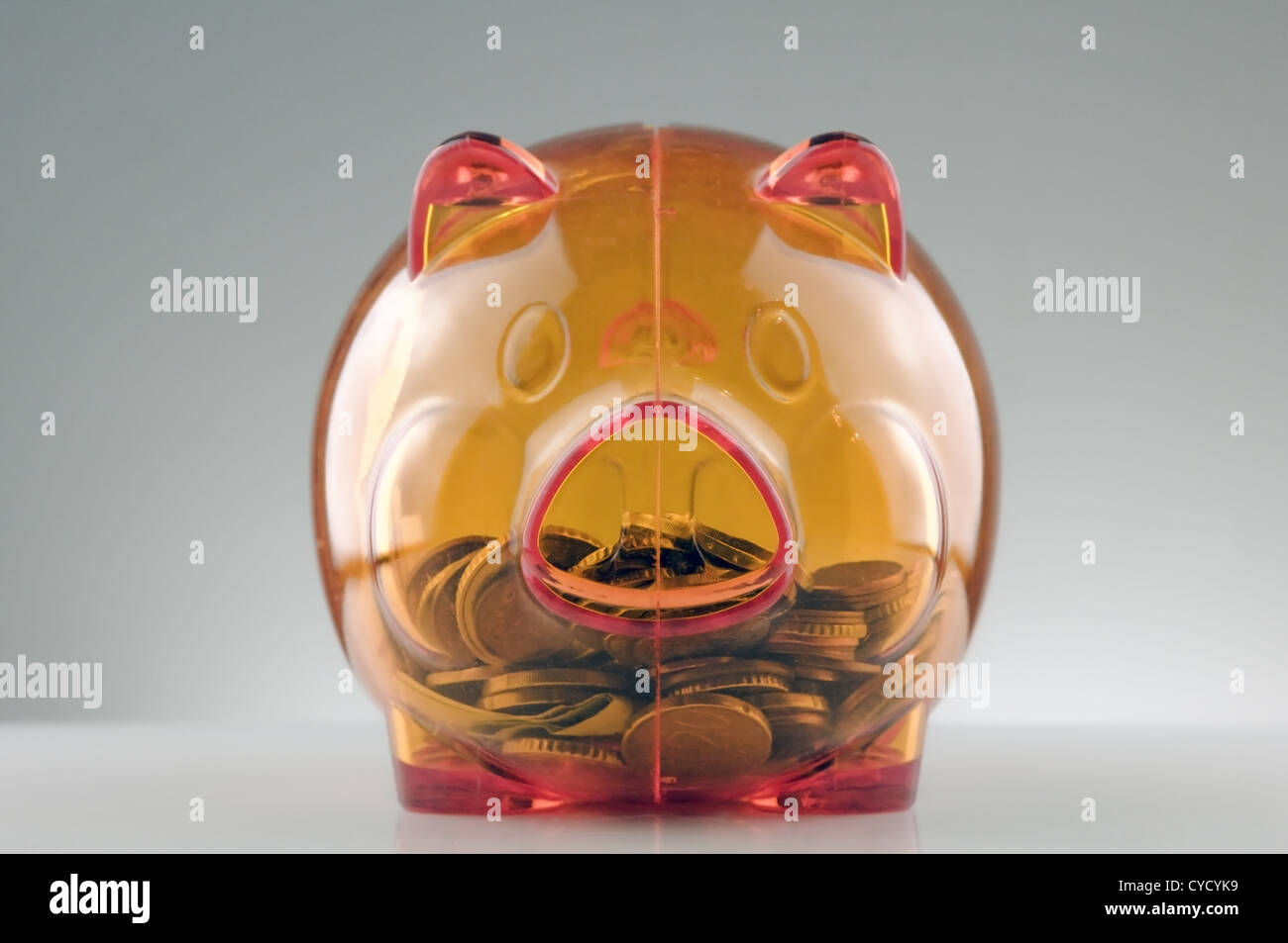 orange translucent piggy bank and coins Stock Photo