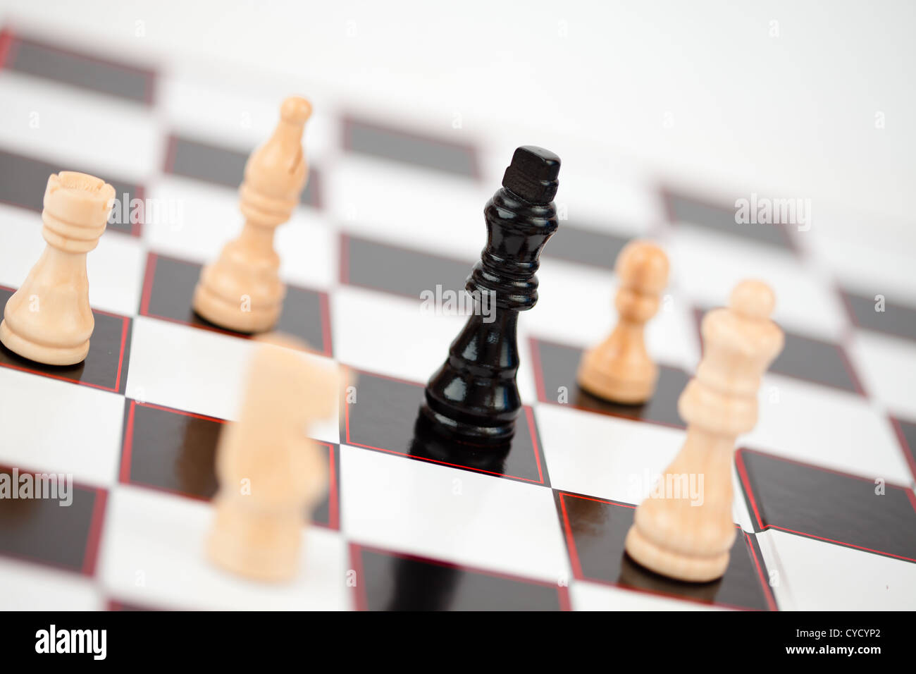 Black queen surrounded by white chess pieces Stock Photo