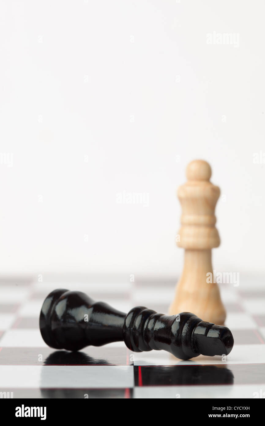 Black chess piece lying while white standing Stock Photo