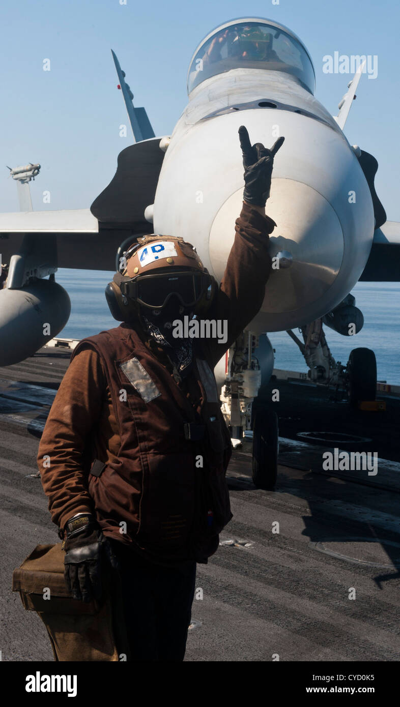 A plane captain signals to directors that an F/A-18C Hornet assigned to the "Golden Dragons" of Strike Fighter Squadron (VFA) 192 is ready to be moved on the flight deck of aircraft carrier USS John C. Stennis (CVN 74). John C. Stennis is deployed to the 5th Fleet area of responsibility conducting maritime security operations, theater security cooperation efforts and support missions for Operation Enduring Freedom. Stock Photo