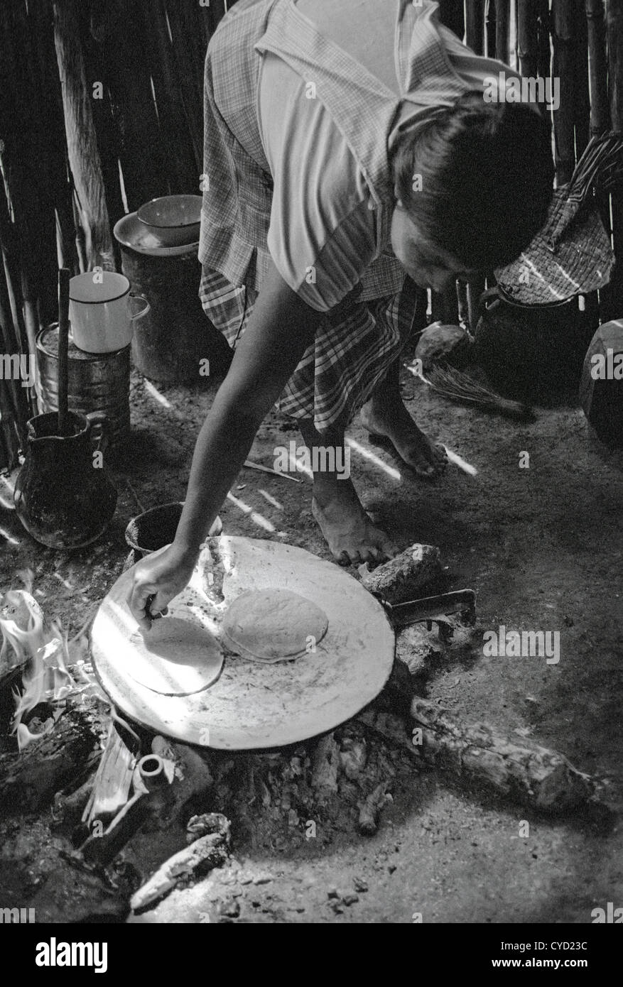 Black and white documentary photo of Kekchi woman cooking tortillas on