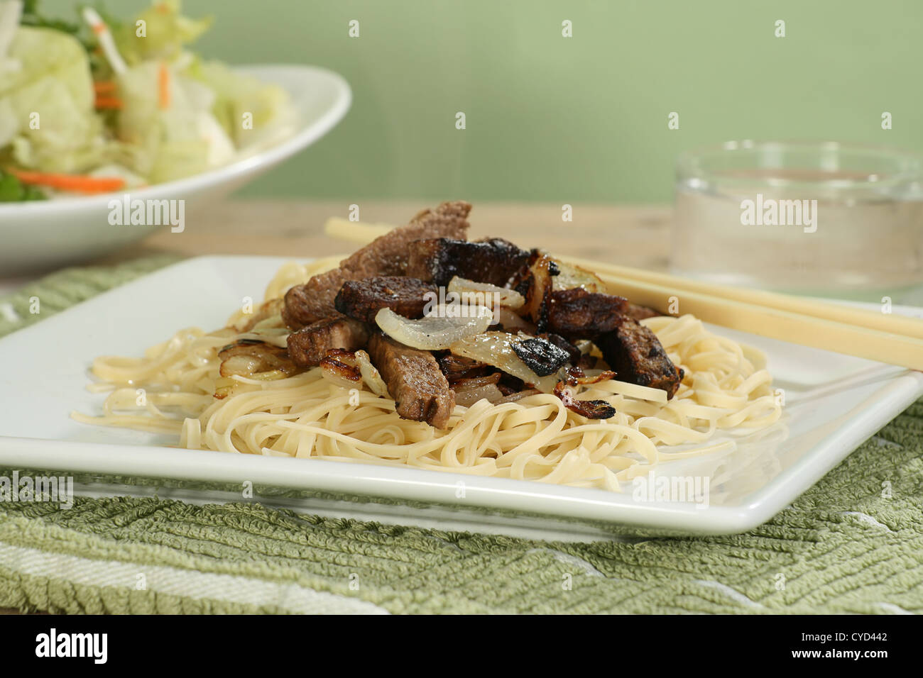 Cooked steak strips with onions on a bed of noodles Stock Photo Alamy