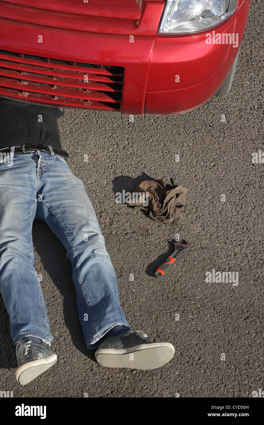 Man lying under his car trying to repair a defect Stock Photo