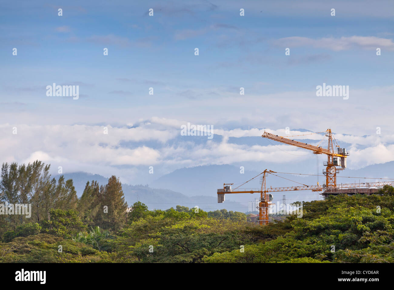 View looking North towards mist covered Genting Highlands, Malaysia. Beam cranes in foreground building new development. Stock Photo