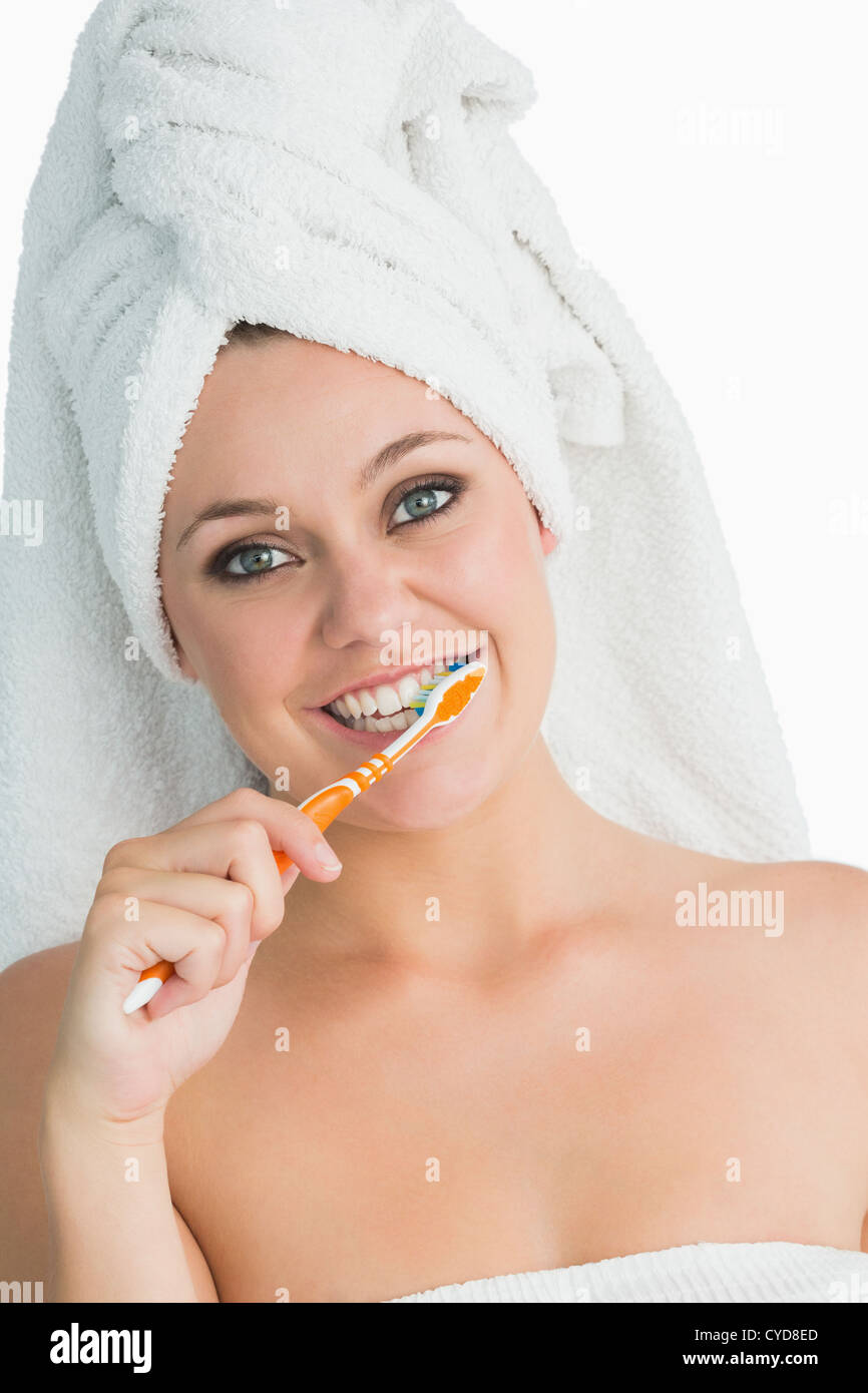 Smiling woman with hair towel washing her teeth Stock Photo