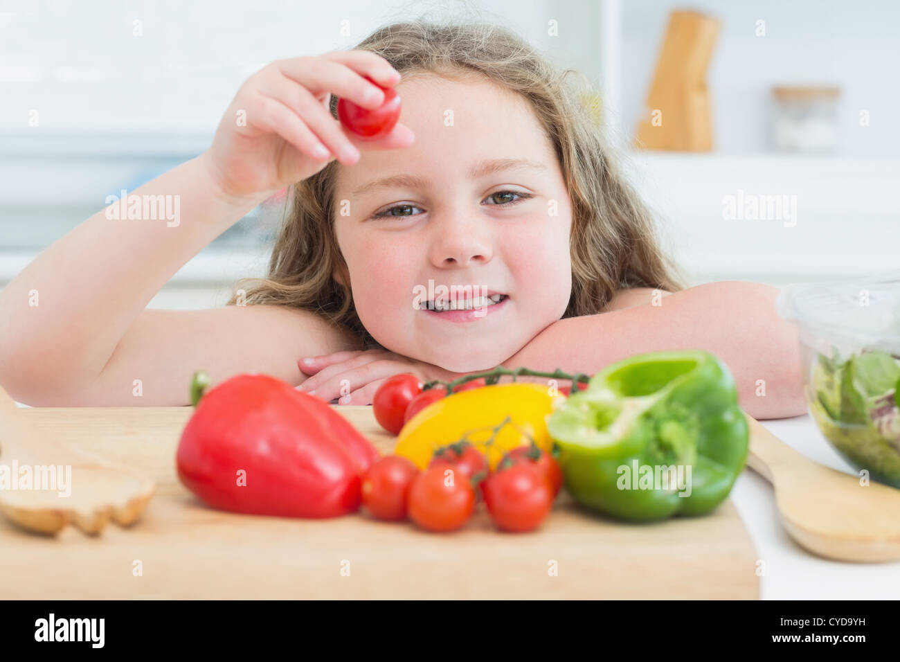 Little girl holding up cherry tomato Stock Photo
