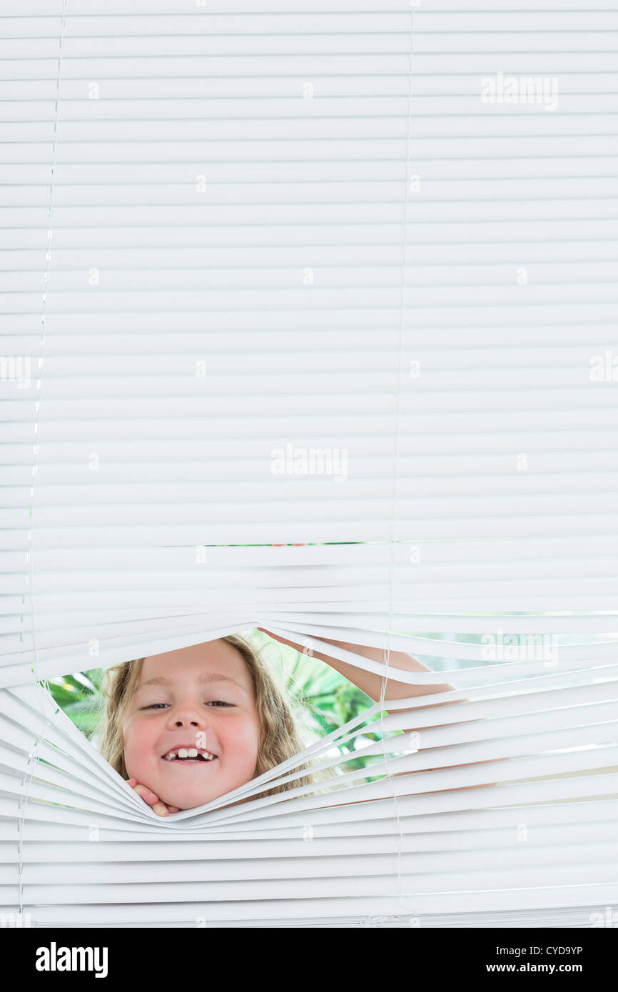Girl peeking out of blinds Stock Photo