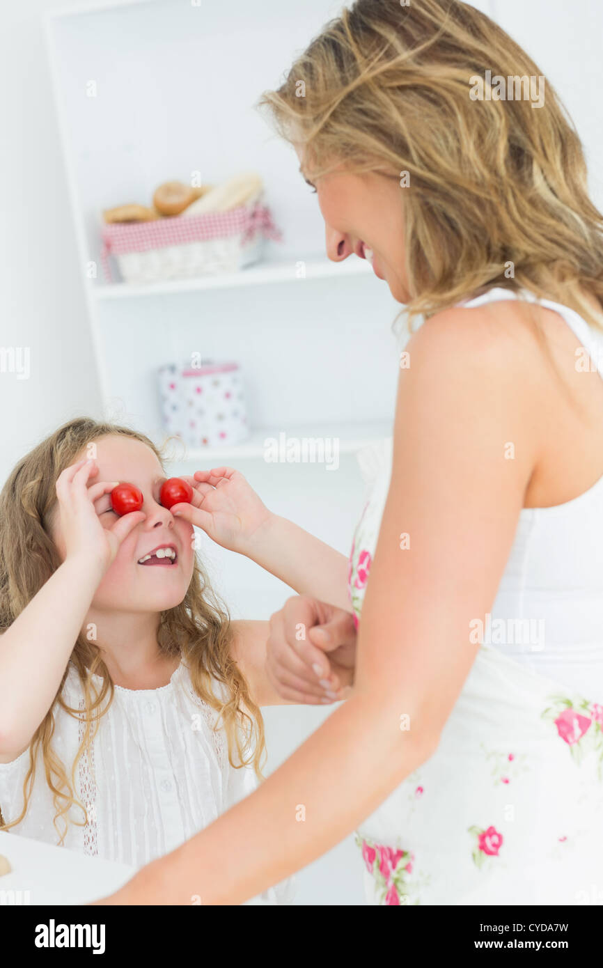 Daughter using cherry tomatoes for eyes Stock Photo