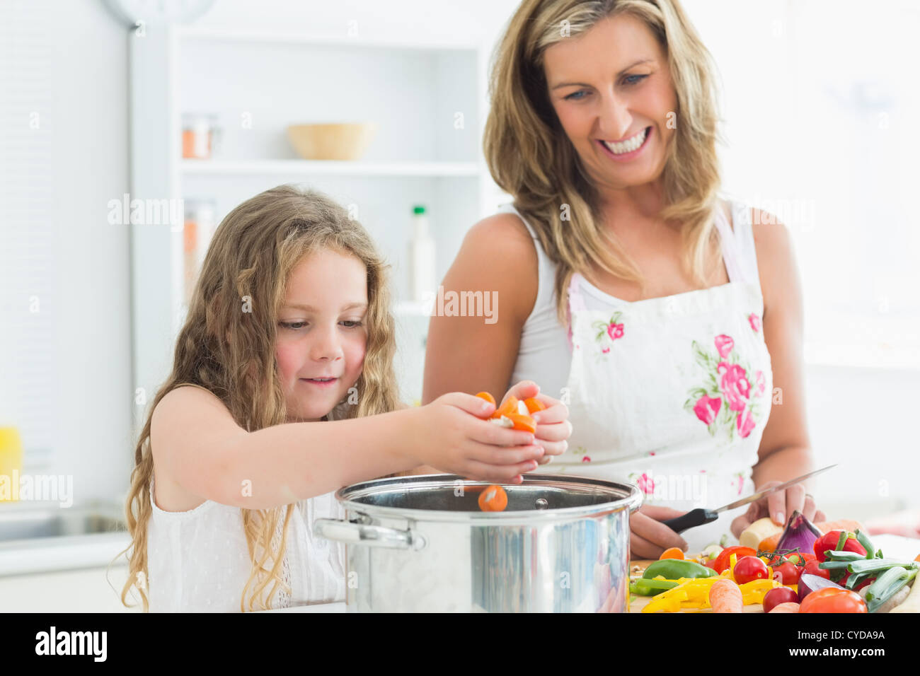 Smiling mother and daughter working at the kitchen Stock Photo