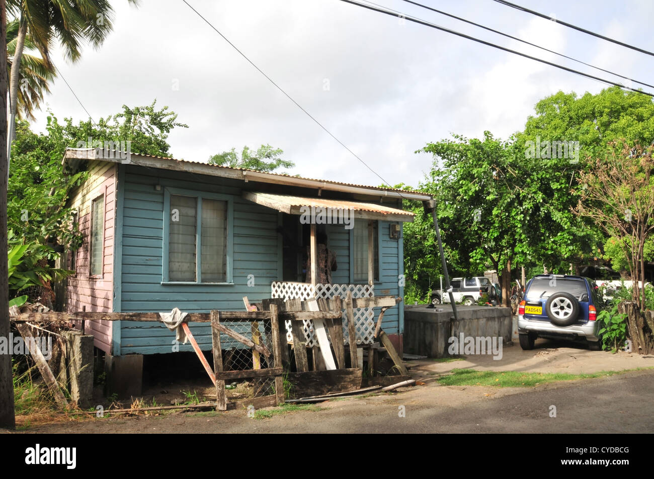 Morning sun view man standing doorway porch blue painted wooden planks house, Belair Road, Hillsborough, Carriacou, West Indies Stock Photo