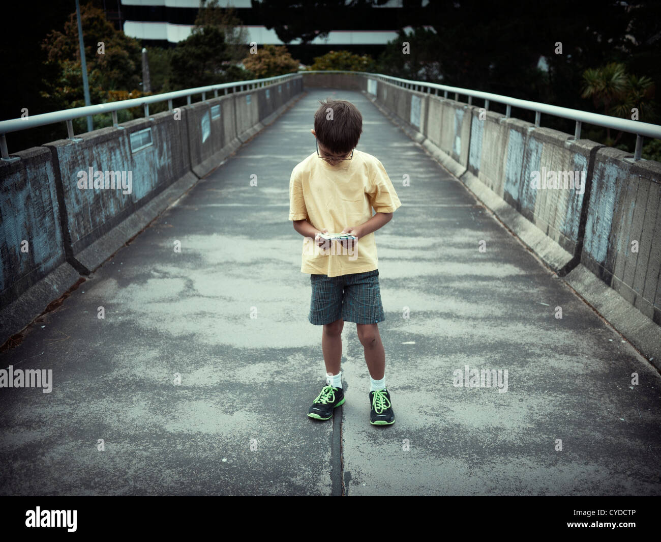 Map reading: boy checks direction on concrete footbridge. Stock Photo