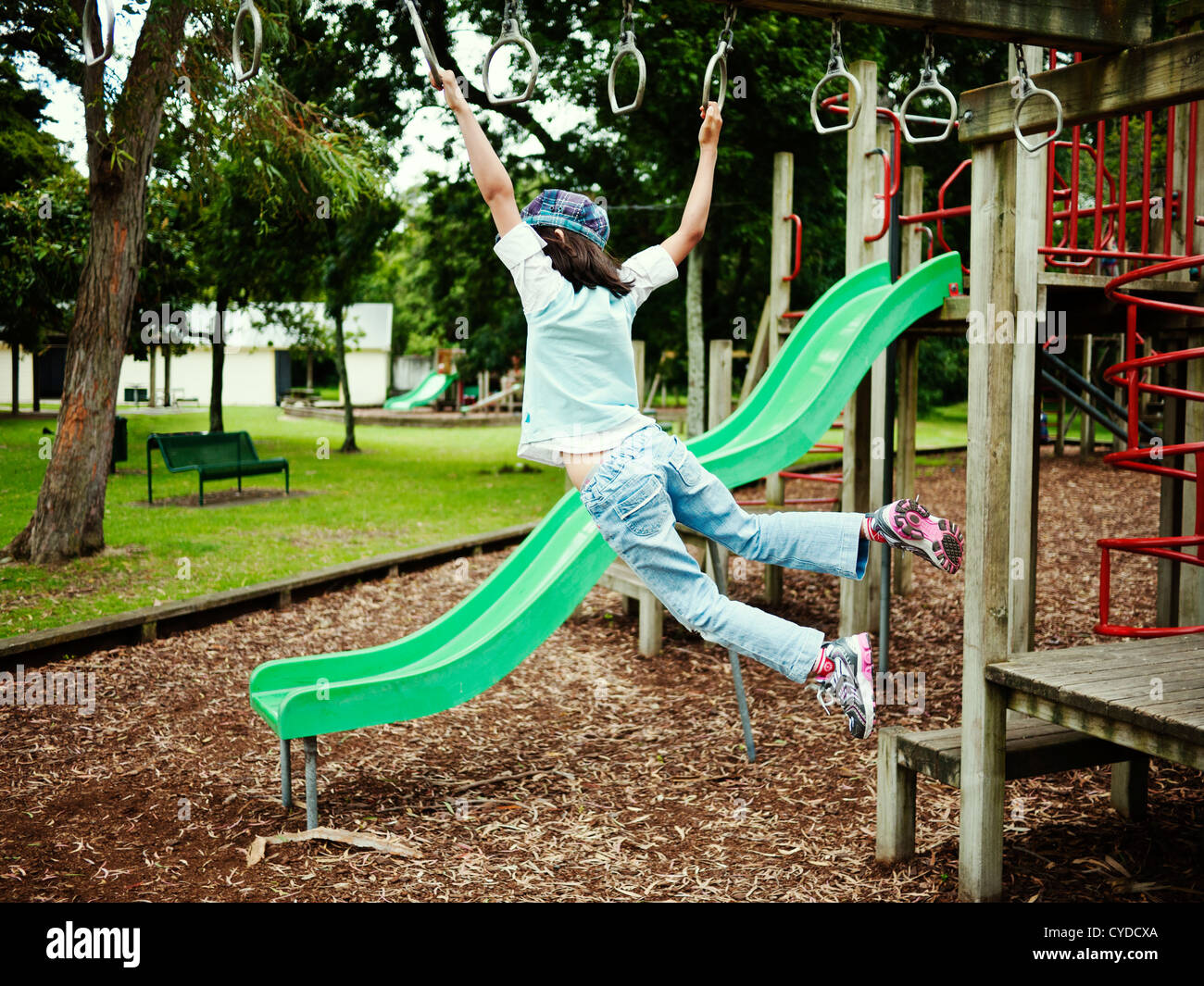 Children swing on monkey bars in adventure playground, New Zealand