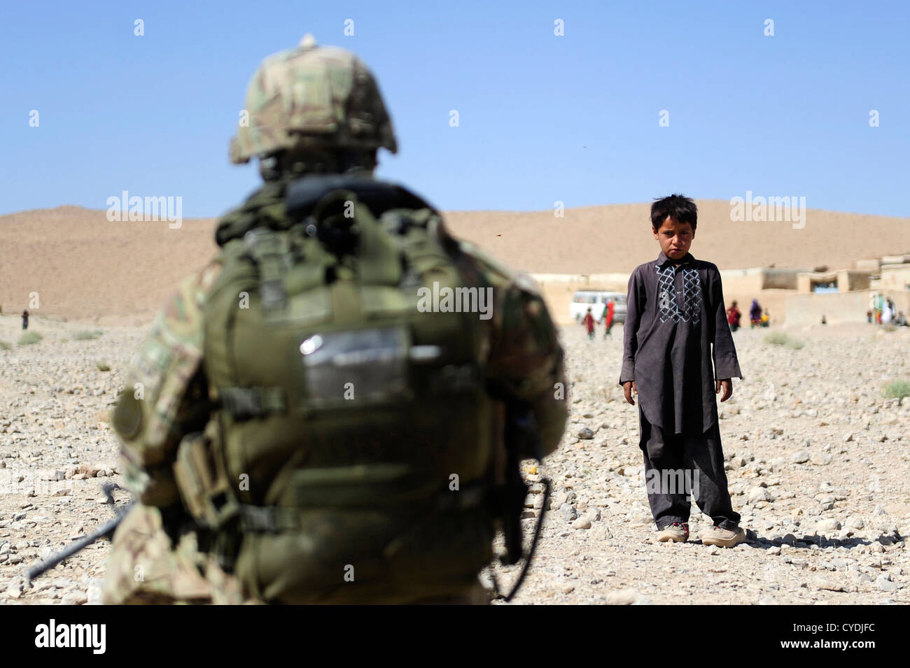 A local Afghan boy watches as members of the US Army and Navy make their way through his village September 26, 2012 in Pur Chaman district, Farah province, Afghanistan. The Provincial Reconstruction Team Farah marks the first time coalition forces have been to the Pur Chaman district in over a year. Stock Photo