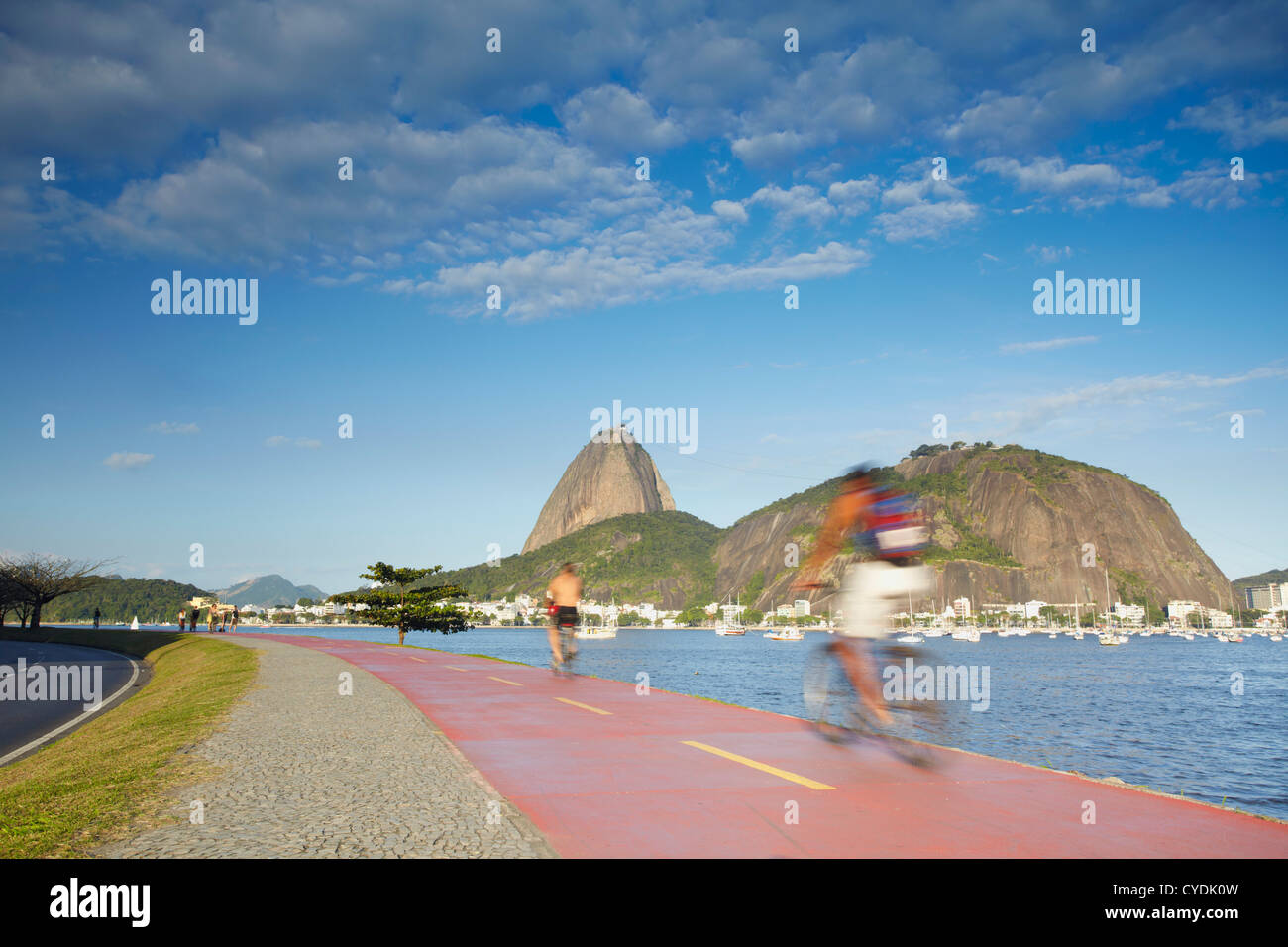 Cyclists on pathway around Botafogo Bay with Sugar Loaf Mountain (Pao de Acucar) in the background, Rio de Janeiro, Brazil Stock Photo