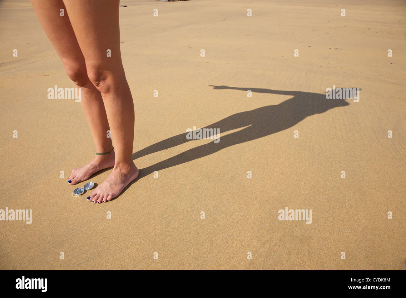 woman legs and shade with compass in a beach Stock Photo