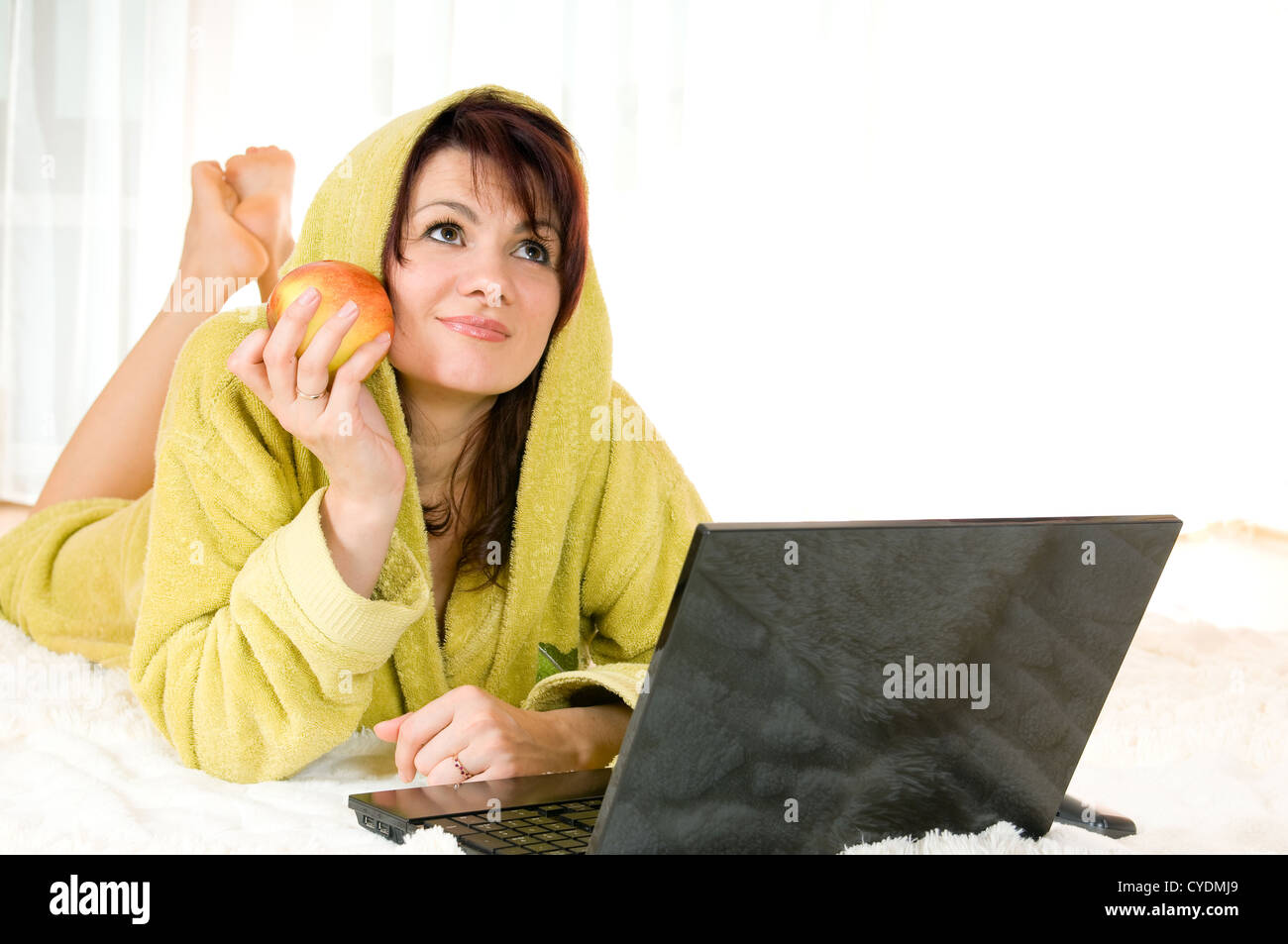 Woman in robe with laptop and apple lying on the floor Stock Photo Alamy