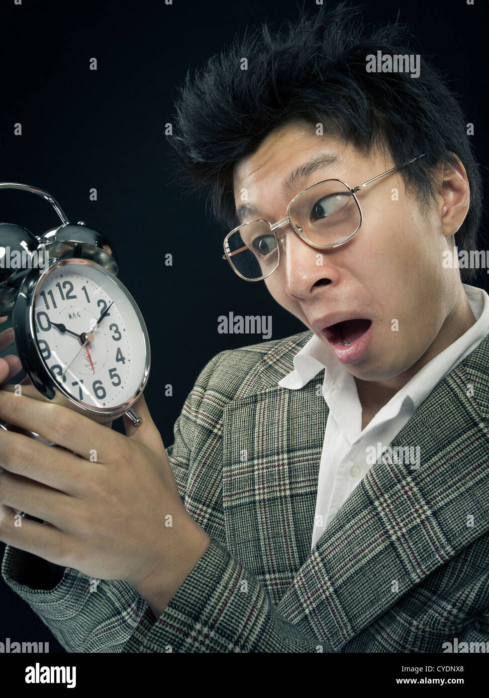 Asian man looking at alarm clock Stock Photo Alamy