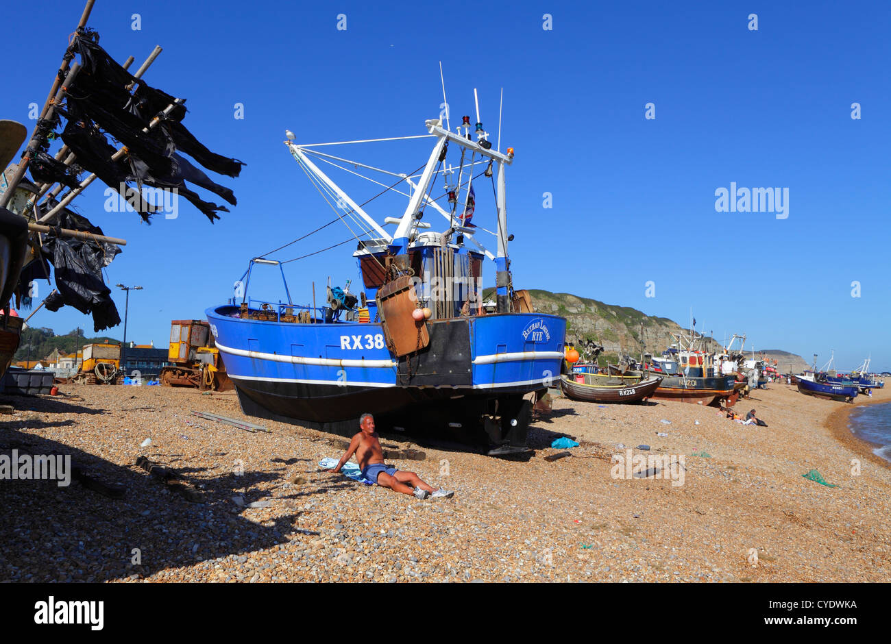 Man sunbathing beside the fishing boats Hastings beach East Sussex UK ...