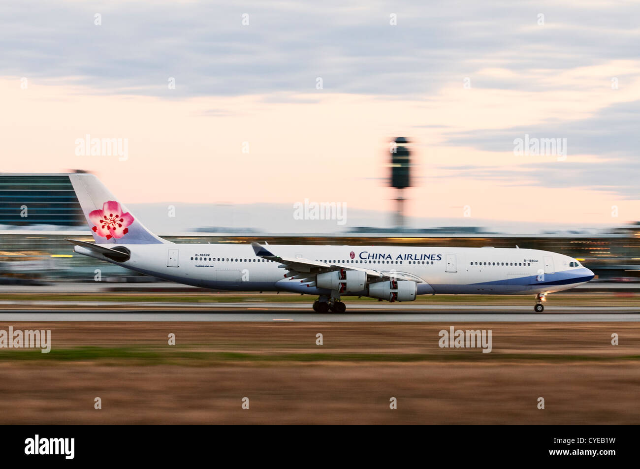 China Airlines Airbus A340-300 (B-18802) airliner blurred by camera panning at slow shutter speed with the landing aircraft. Stock Photo