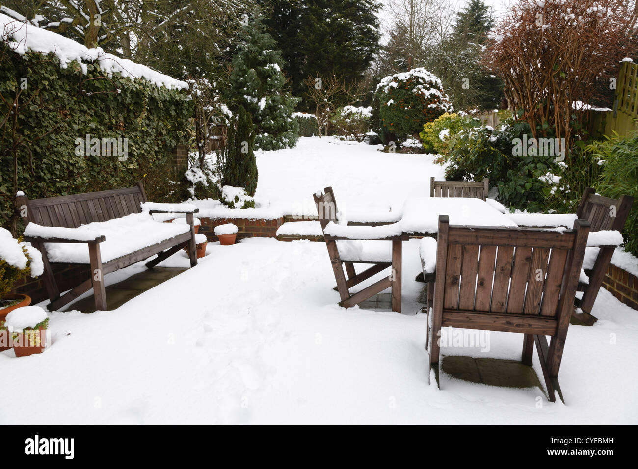 Suburban snow covered patio with garden furniture, garden in the