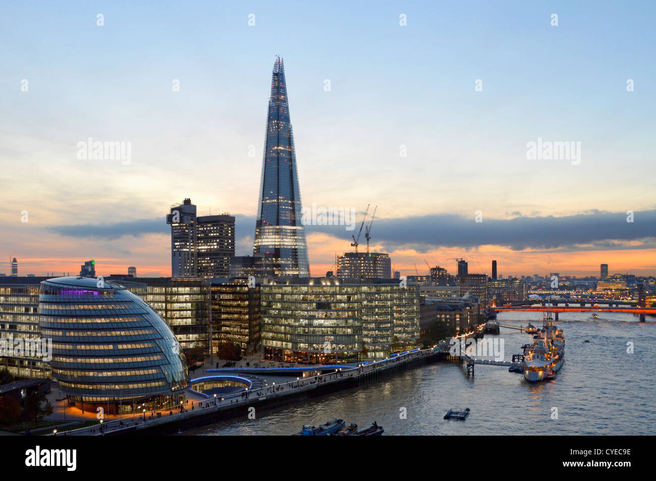 London skyline (L to R) City Hall, 'More London' (with The Scoop) Guys Hospital The Shard River Thames HMS Belfast office lights on dusk sunset UK Stock Photo