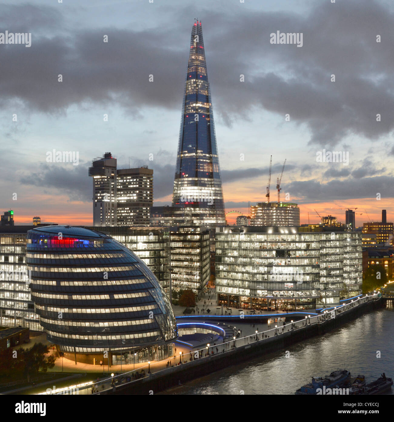 London skyline with (L to R) City Hall, "More London" (with The Scoop) Guys Hospital & The Shard River Thames office lights on dusk sunset England UK Stock Photo