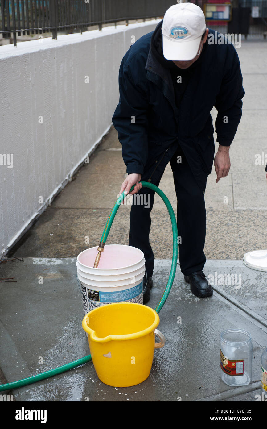 Residents without power from Hurricane Sandy fill buckets of water to cook  and flush toilets with at a hose set up for them Stock Photo - Alamy