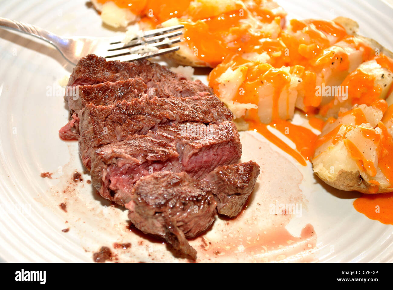 Rare Sliced Filet Mignon and French Dressing on a Baked Potato Stock