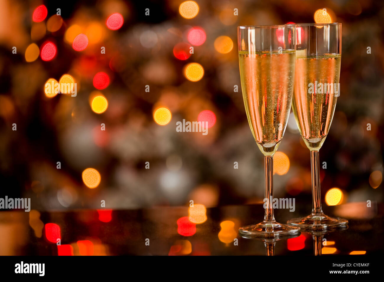 photo of two champagner glasses on glass table with bokeh background