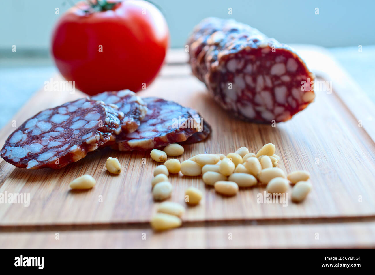 Sausage, tomato, pine nuts on  wooden board close up Stock Photo