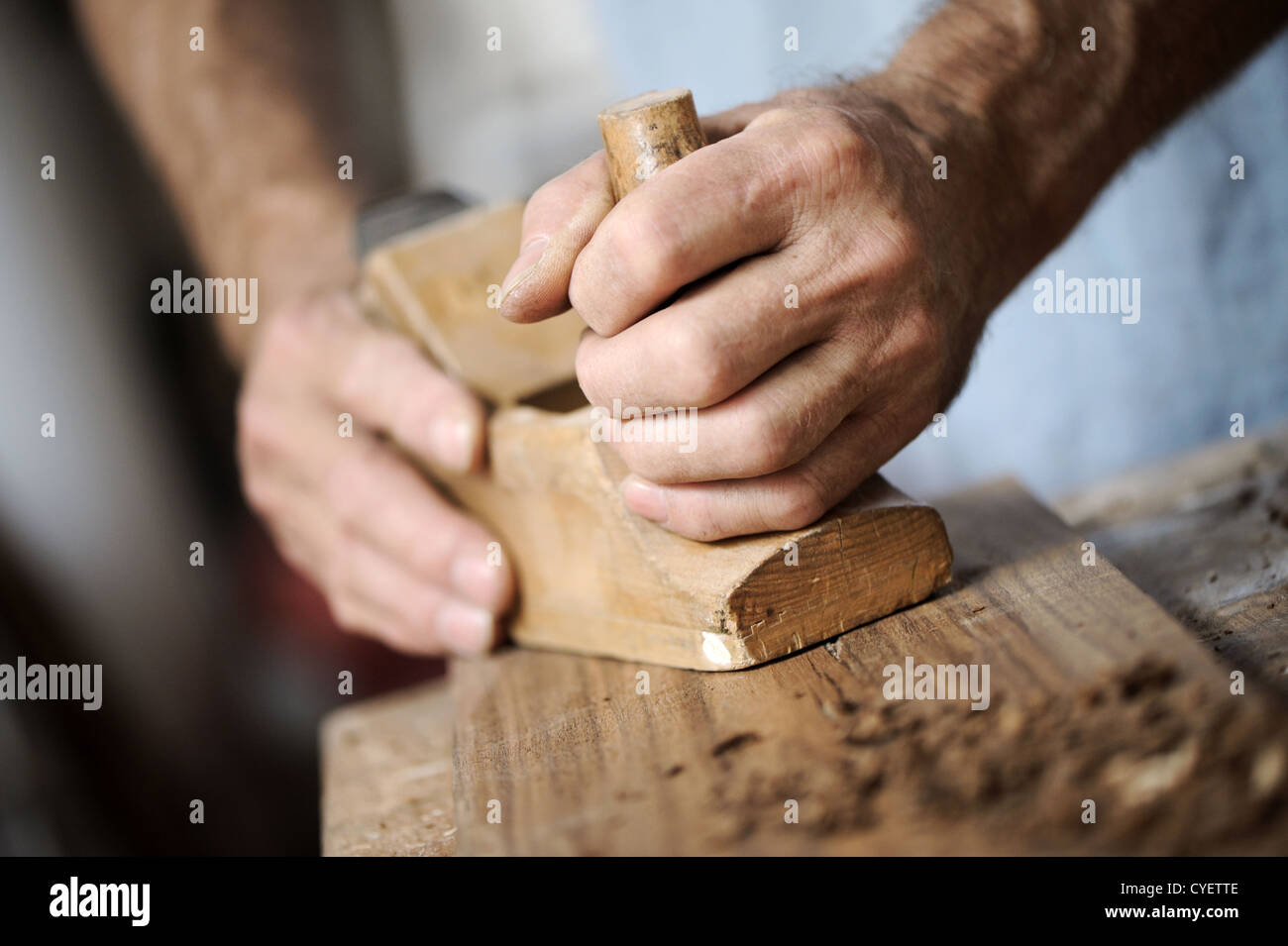 hands of a carpenter planing a plank of wood with a hand plane Stock