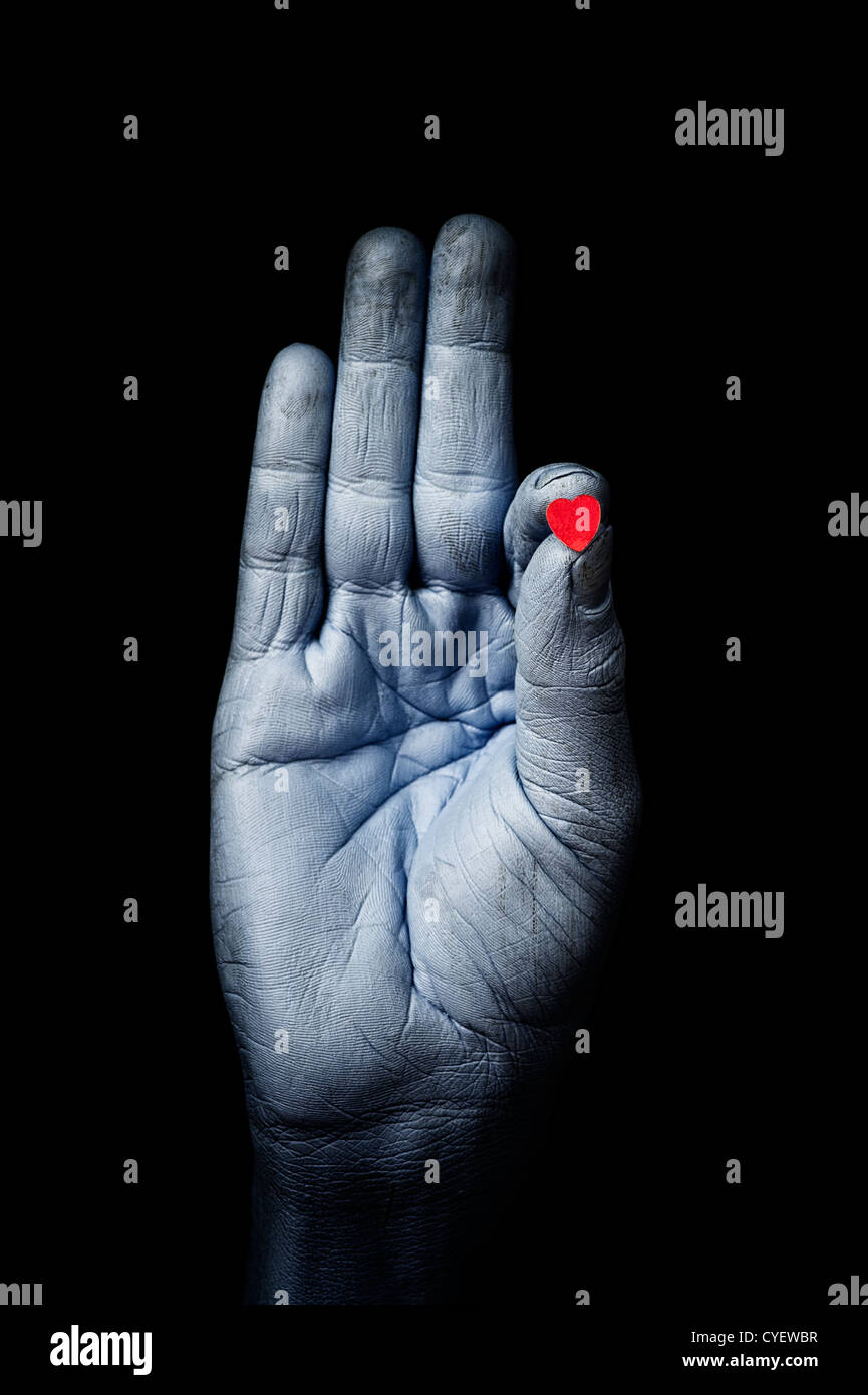 Blue painted hand in buddha hand pose holding a love heart against a black background Stock Photo