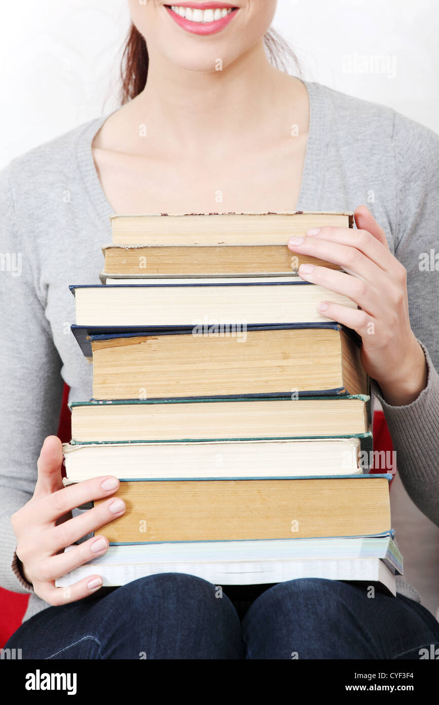 Smiling female student holding a pile of books Stock Photo - Alamy