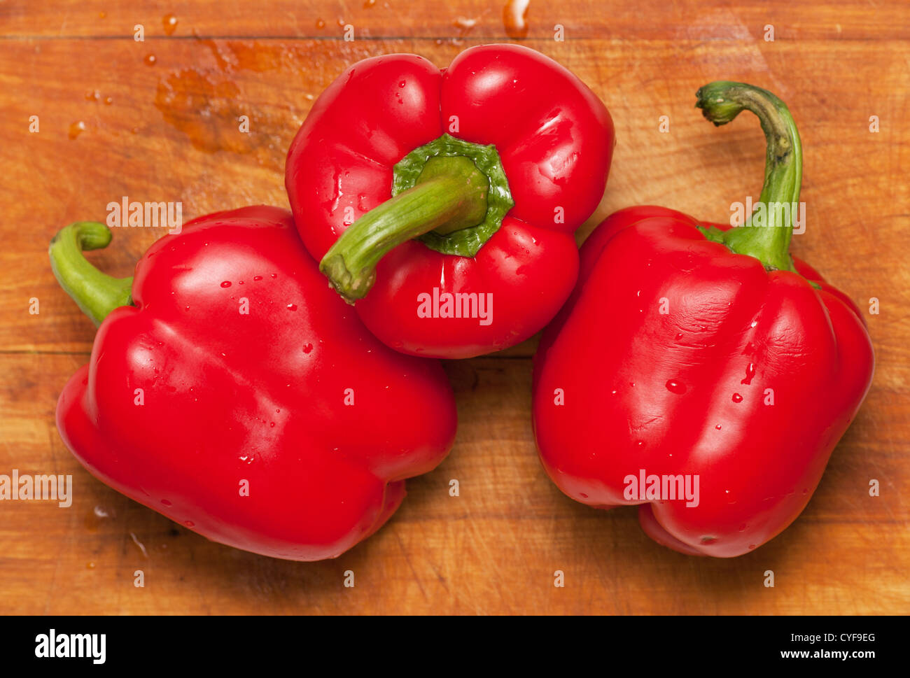 Three sweet red peppers on a cutting board Stock Photo - Alamy