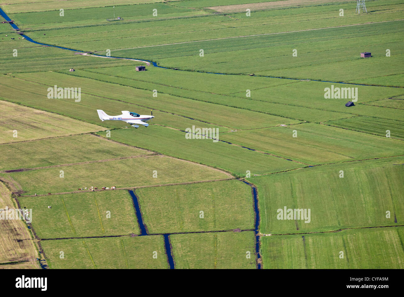 The Netherlands, Muiden. Small airplane flying over farmland. Aerial. Stock Photo